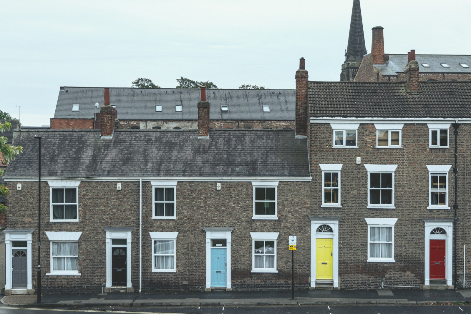 A row of brick terraced townhouses with bay windows on a quiet street